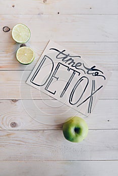 top view of time to detox card and fresh limes and apple