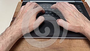 Top view timelapse of caucasian male fingers typing on a laptop computer keyboard.