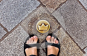 Top view of tired tourist legs in sandals and brass crown marker in cobblestone streets