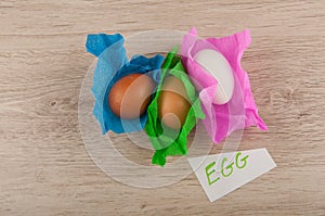 Top view title and chicken eggs in paper laying on wooden table