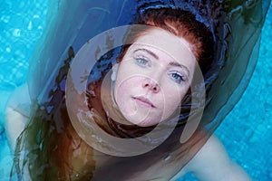 Top view to a beautiful young sexy erotic seductive redhead woman portrait lying in the water of the spa wellness pool, lightly