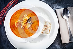 Top view on tom yum soup served in white plate with rice. soup with shrimp, seafood, coconut milk and chili pepper in bowl copy