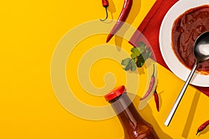 Top view of tomato sauce with hot chili peppers and cilantro on yellow background