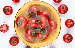 top view of tomatoes in bowl with cut and whole ones on wooden background