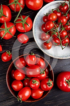 top view of tomatoes in bowl and plate and other ones on wooden background