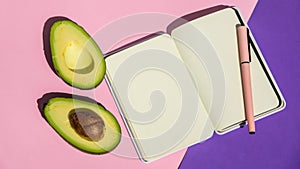 Top view. Top view An empty notepad and sliced avocado on a pink background Top view.