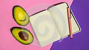 Top view. Top view An empty notepad and sliced avocado on a pink background Top view.