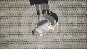 Top view, tough stylish caucasian man street dancer dancing break dance on the background urban tiles. Guy is performing freestyle