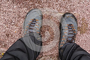 Top view of a tourist`s wet and dirty approach shoes and pants on a stone trail