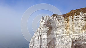 Top view of tourists standing at peak of white cliff on sea. Action. Spectacular views of massive white cliff, blue sea