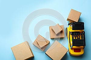 Top view of toy forklift with boxes on background, space for text. Logistics and wholesale concept