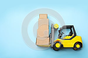 Top view of toy forklift with boxes on background, space for text. Logistics and wholesale concept