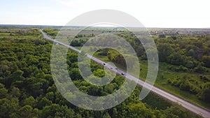 Top view of track with traffic on background of green trees. Shot. Landscape highway with passing cars on background of