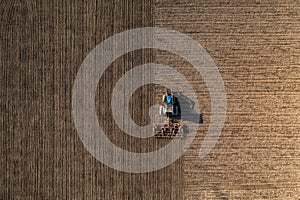 Top view of a tractor harrowing soil on an agriculture field.