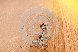 Top View Tractor Plowing Field In Spring Season. Beginning Of Agricultural Spring Season. Cultivator Pulled By A Tractor