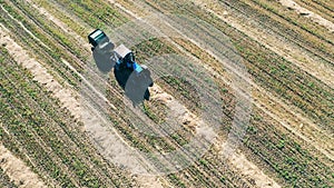 Top view of a tractor riding along the field and haymaking
