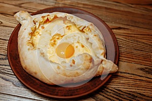 Top view on traditional Adjarian Khachapuri - open baked pie with melted salt cheese suluguni and egg yolk on wooden