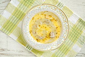 Top view of a traditional bulgarian chicken soup dish pileshka chorba, thickened with egg on a green napkin on a white wooden