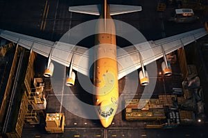 Top view of a transport aircraft in the cargo terminal of the airport. Crates and containers are ready to be loaded onto