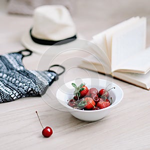 Top view travel or vacation concept. Swimsuit, hat, book and cherries  on wooden background.  Flatlay. Summer background.