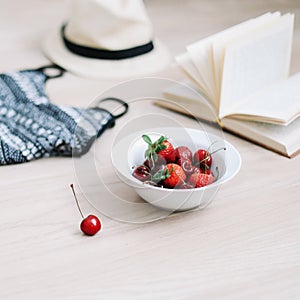 Top view travel or vacation concept. Swimsuit, hat, book and cherries  on wooden background.  Flatlay. Summer background.