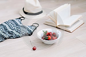 Top view travel or vacation concept. Swimsuit, hat, book and fresh sweet berries.  Flatlay. Summer background.