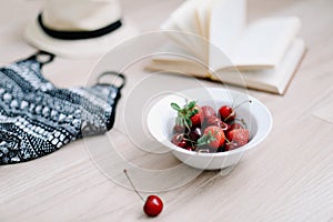 Top view travel or vacation concept. Swimsuit, hat, book and fresh sweet cherries and strawberries.  Flatlay. Summer background.