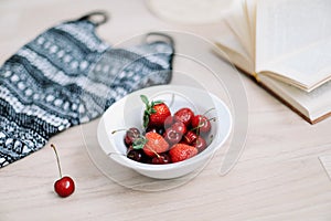 Top view travel or vacation concept. Swimsuit, hat, book and fresh sweet cherries and strawberries.  Flatlay. Summer background.