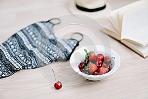 Top view travel or vacation concept. Swimsuit, hat, book and fresh sweet cherries and strawberries.  Flatlay. Summer background.