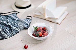 Top view travel or vacation concept. Swimsuit, hat, book and fresh sweet cherries and strawberries.  Flatlay. Summer background.