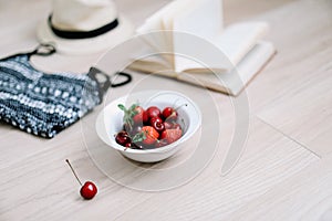 Top view travel or vacation concept. Swimsuit, hat, book and fresh sweet cherries and strawberries.  Flatlay. Summer background.