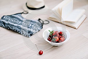 Top view travel or vacation concept. Swimsuit, hat, book and fresh sweet cherries and strawberries.  Flatlay. Summer background.