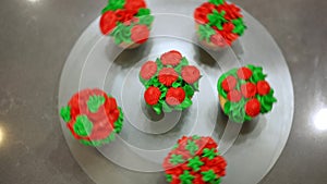 Top view tray with delicious cupcakes with green and red icing and female hand spinning dessert in slow motion. Tasty