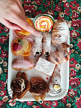 Top view a tray pastry cakes with a view of a hand point