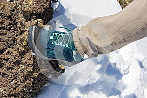 Top view of trekking shoes on the lava stone and snow background, female legs