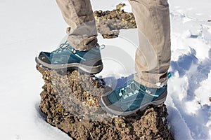 Top view of trekking shoes on the lava stone and snow background, female legs