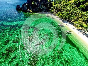 Top view of a tropical island with palm trees and blue clear water. Aerial view of a white sand beach and boats over a coral reef