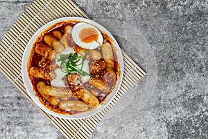 Top view Tteokbokki Spicy Rice Cakes with boiled eggs and cheese on the grey concrete table, Korean street food