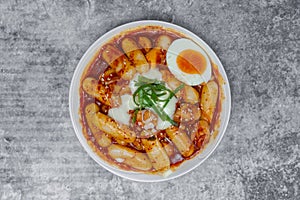 Top view Tteokbokki Spicy Rice Cakes with boiled eggs and cheese on the grey concrete table, Korean street food