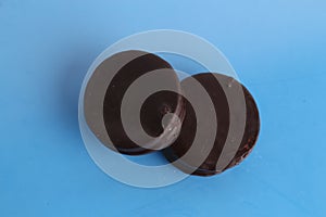 Top view of two chocolate biscuits with dulce de leche on a blue surface