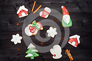 Top view of two cups of hot cocoa, ginger snowflake cookie, red gift boxes and fir tree branches on wooden background.