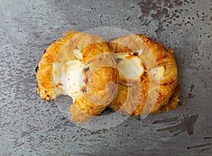 Top view of two delicious cream cheese danishes with one missing a bite on a gray mottled tabletop