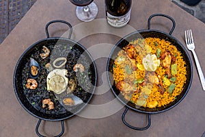 Top view of two dishes of Paella and Arros negre served in a restaurant