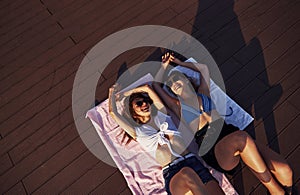Top view of two girls on the beach that lying down on the ground and enjoying warm sunlight