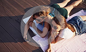 Top view of two girls on the beach that lying down on the ground and enjoying warm sunlight