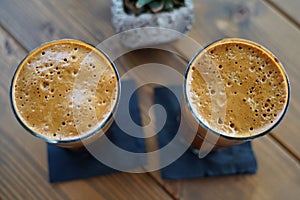 Top view of two glasses of iced cold frappes on a wooden table photo