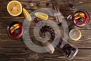 Top view of two glasses with mulled wine with an orange peel and a slice of lemon, cinnamon sticks, a jar of dried fruits on a