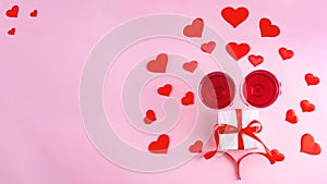 Top view of two glasses with rose wine, gift with red ribbon and red hearts on pink background, banner, copy space