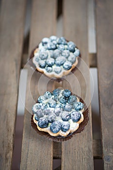 Top view of two mascarpone pies with blueberries on the top on a wooden table in soft focus