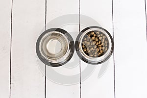 Top view of two metal bowls, one with dog food and the other with water. Pets indoors. Home or studio. Love for animals concept